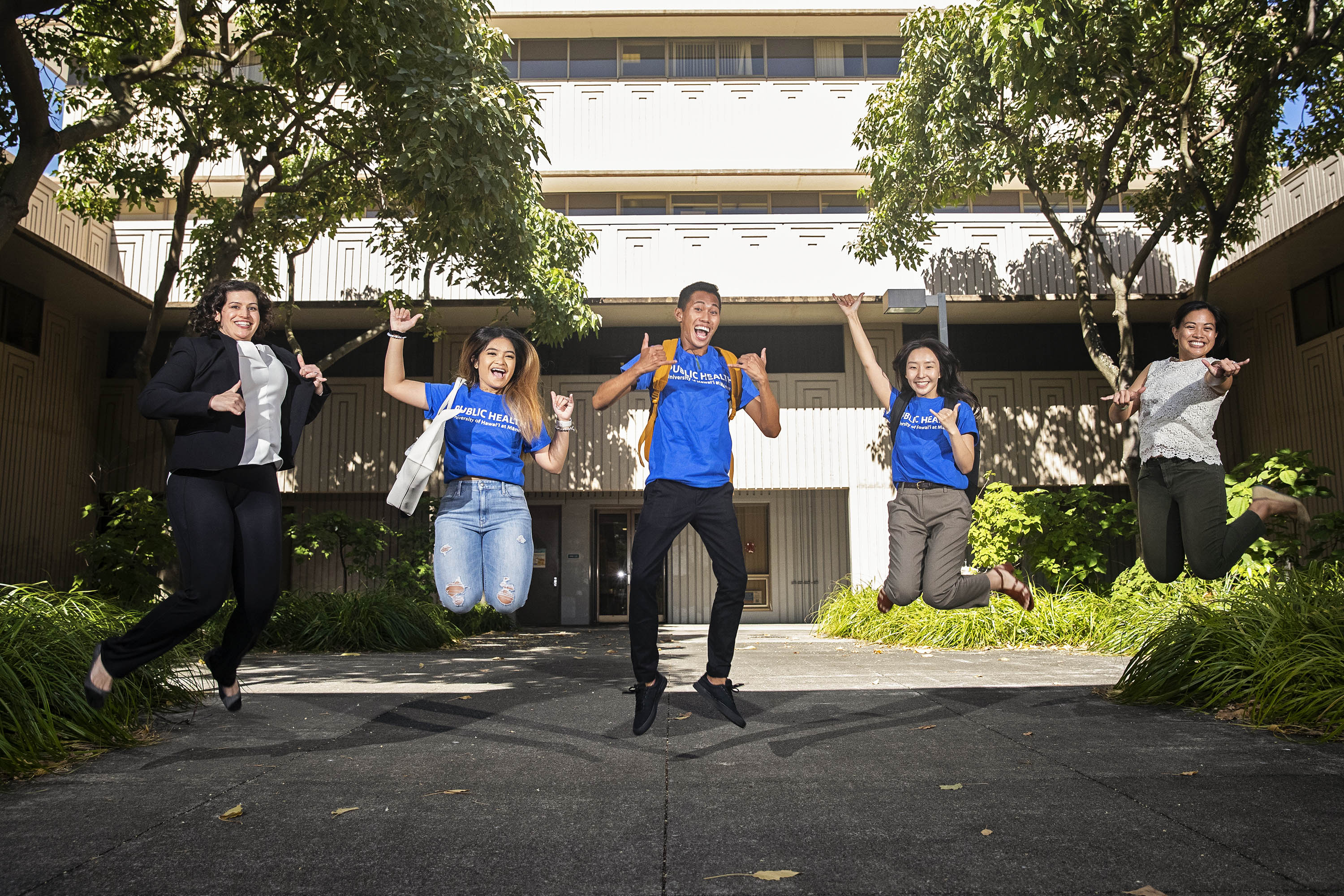 Five students exuberantly jumping in the air.