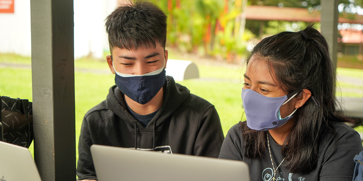 Two students in masks at laptops