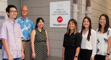 Students flank Shidler College of Business Dean Vance Roley, second from left, in front of the newly-renovated Office of Internships and Career Development.
