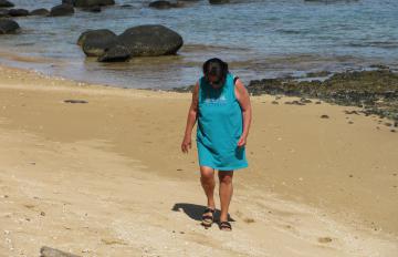 Fran walks along Tunnels Beach on Kauai searching for seashells
