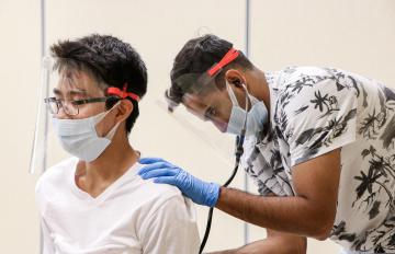 A medical student at the John A. Burns School of Medicine listens to a patient using a stethoscope.