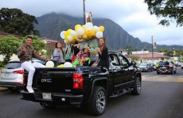 Graduating students at Windward Community College are seen in a pickup truck participating in a commencement caravan on campus.