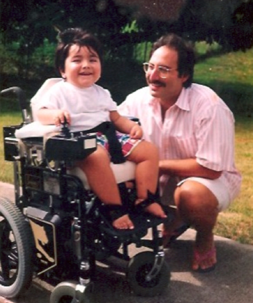A young Kal Warrington Silvert in a wheel chair spending time with his father